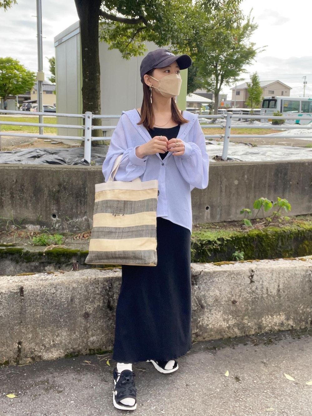 ブラック系のトートバッグ、ブルー系のシャツ/ブラウス、ブラック系のワンピースを着用したレディースの春コーディネートの4枚目の写真