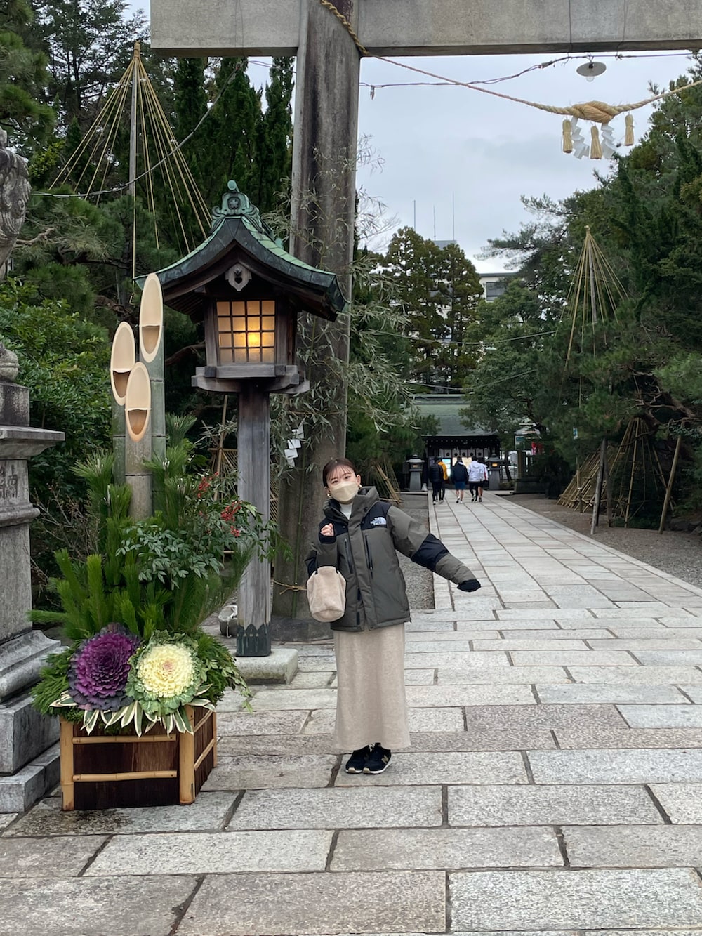 グリーン系のダウンジャケット/コート、ホワイト系のニット/セーター、ベージュ系のスカートを着用したレディースの冬コーディネートの3枚目の写真