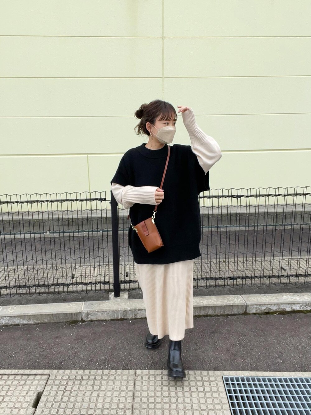 ブラック系のベスト、ホワイト系のワンピース、ブラウン系のショルダーバッグを着用したレディースの秋コーディネートの3枚目の写真