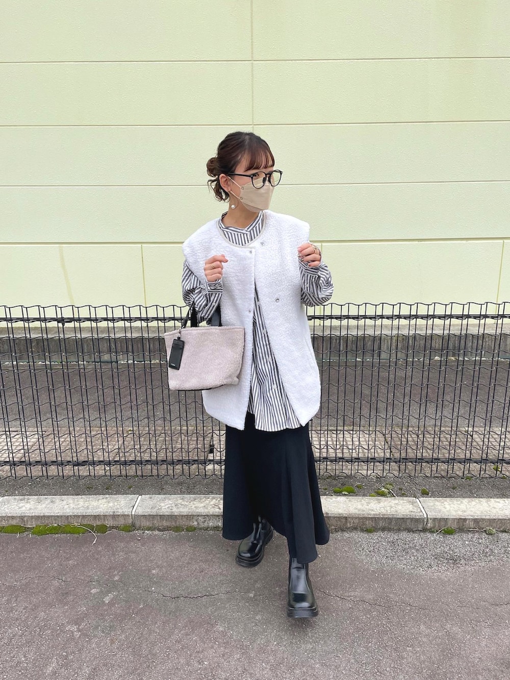 グレー系のトートバッグ、グレー系のシャツ/ブラウス、ホワイト系のベストを着用したレディースの秋コーディネートの4枚目の写真