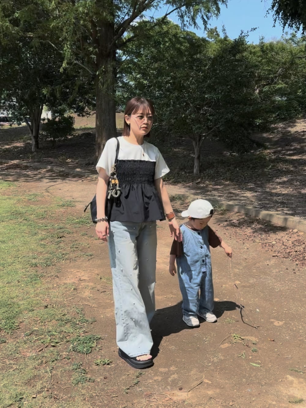 ホワイト系のTシャツ/カットソー、ブルー系のデニムパンツ、ブラック系のバッグを着用したレディースの夏コーディネートの5枚目の写真