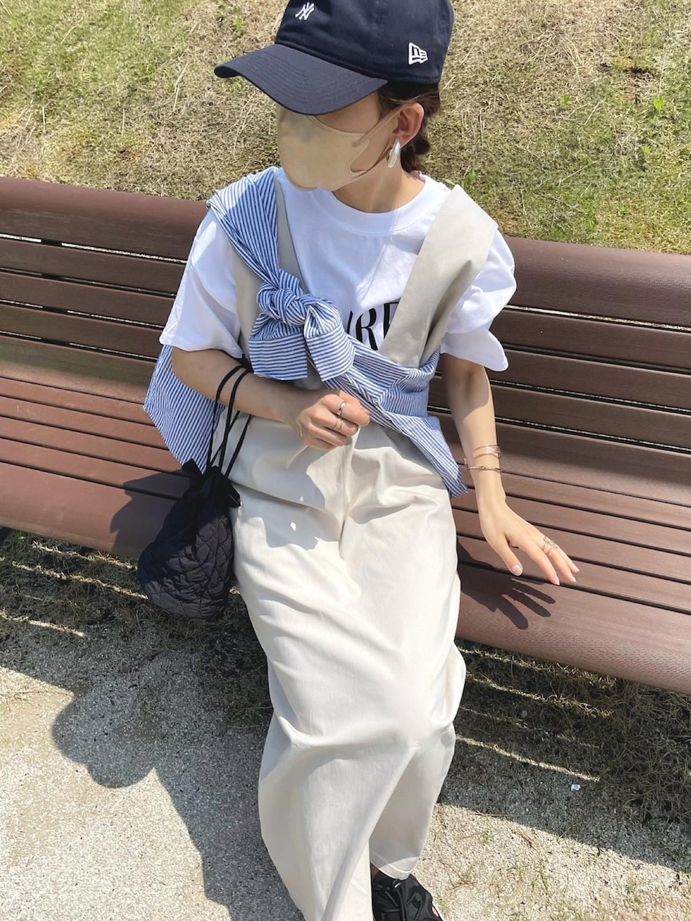 ベージュ系のジャンパースカート、ホワイト系のTシャツ/カットソー、ブルー系のシャツ/ブラウスを着用したレディースの夏コーディネートの3枚目の写真