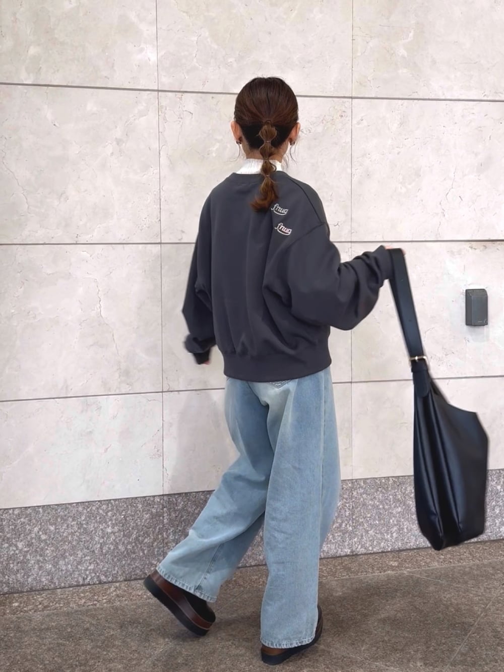 グレー系のスウェット、ホワイト系のニット/セーター、ブルー系のデニムパンツを着用したレディースの冬コーディネートの4枚目の写真