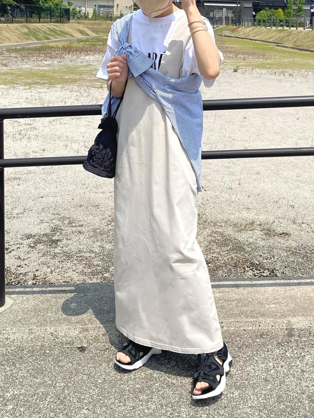 ベージュ系のジャンパースカート、ホワイト系のTシャツ/カットソー、ブルー系のシャツ/ブラウスを着用したレディースの夏コーディネートの2枚目の写真