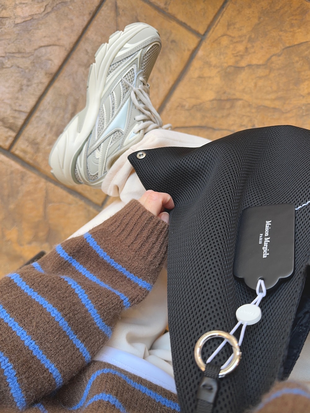 ブラック系のトートバッグ、ブラウン系のニット/セーター、ホワイト系のパンツを着用したレディースの冬コーディネートの4枚目の写真