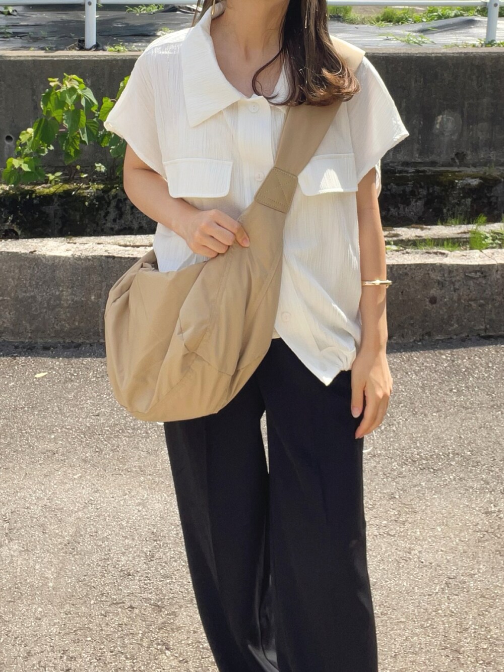 ベージュ系のショルダーバッグ、ブラック系のパンツ、ブラック系のサンダルを着用したレディースの夏コーディネートの4枚目の写真