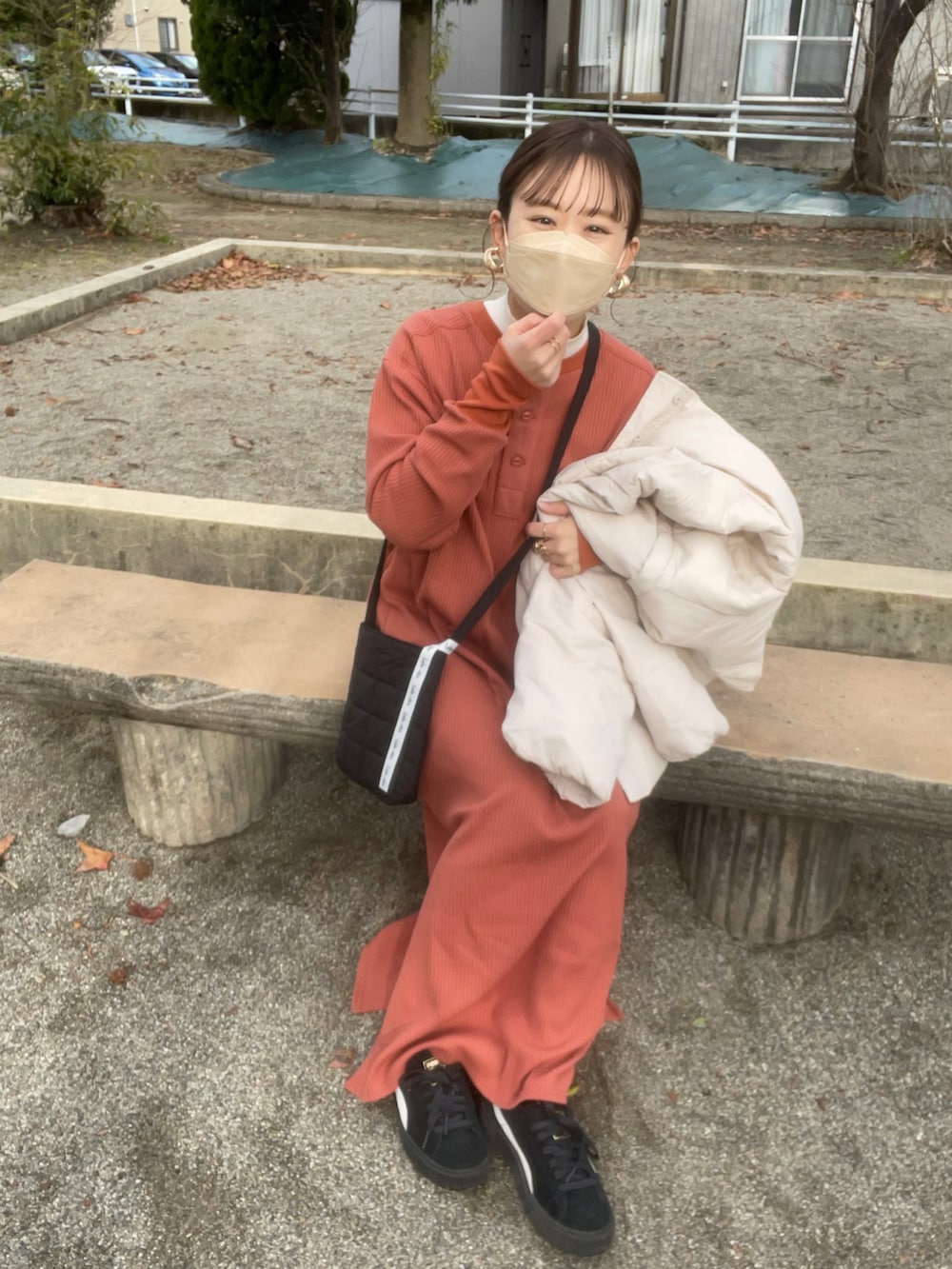 オレンジ系のワンピース、ホワイト系のニット/セーター、ブラック系のショルダーバッグを着用したレディースの冬コーディネートの3枚目の写真