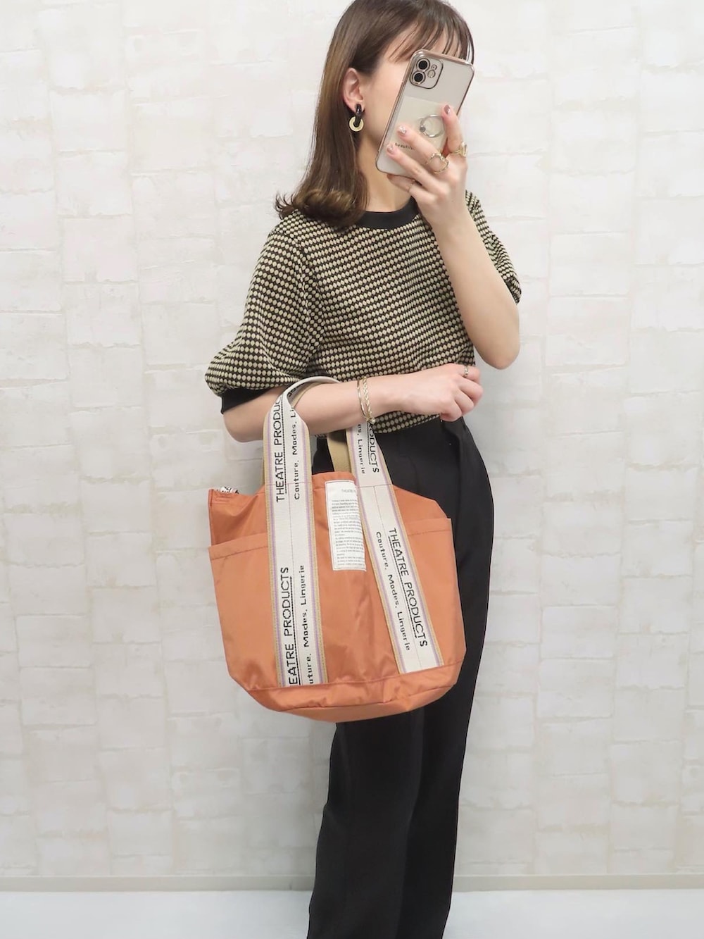 ブラック系のTシャツ/カットソー、オレンジ系のトートバッグ、ブラック系のスラックスを着用したレディースの春コーディネートの2枚目の写真