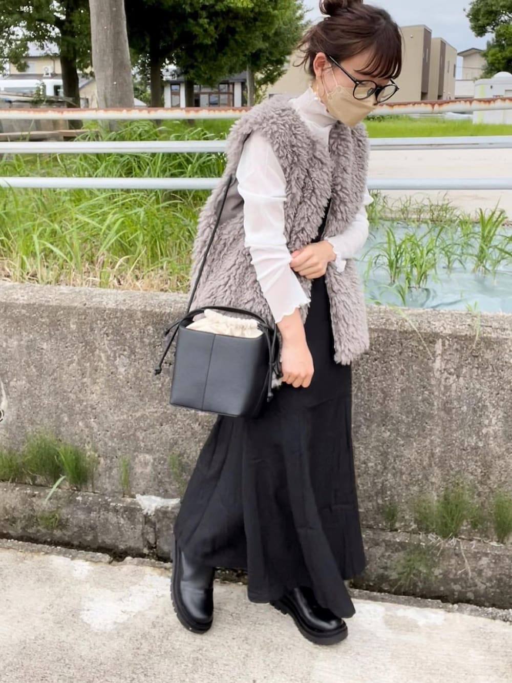 ベージュ系のベスト、ホワイト系のTシャツ/カットソー、ブラック系のジャンパースカートを着用したレディースの秋コーディネートの2枚目の写真