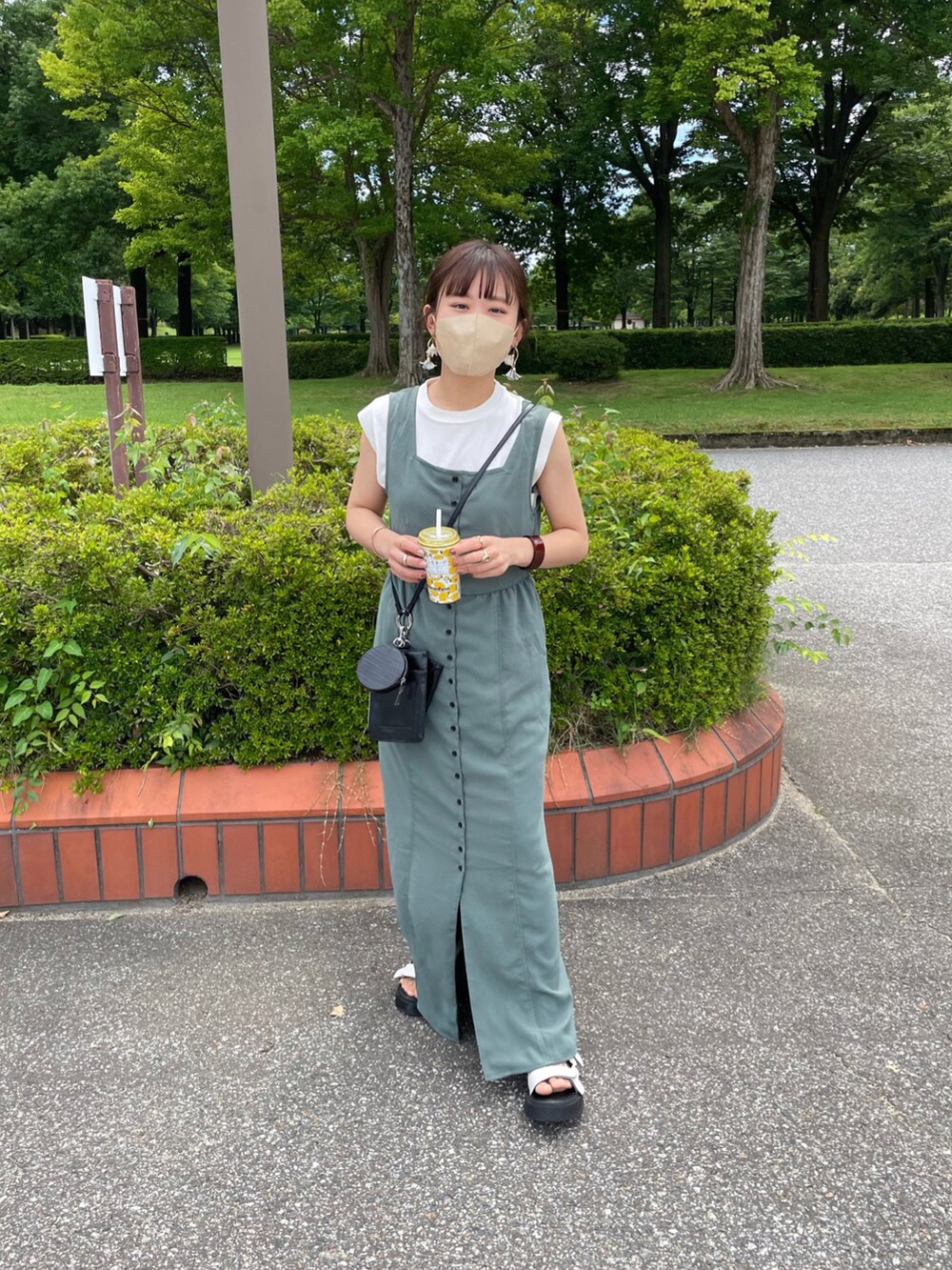 グリーン系のワンピース、ホワイト系のニット/セーター、ブラック系のショルダーバッグを着用したレディースの夏コーディネートの4枚目の写真