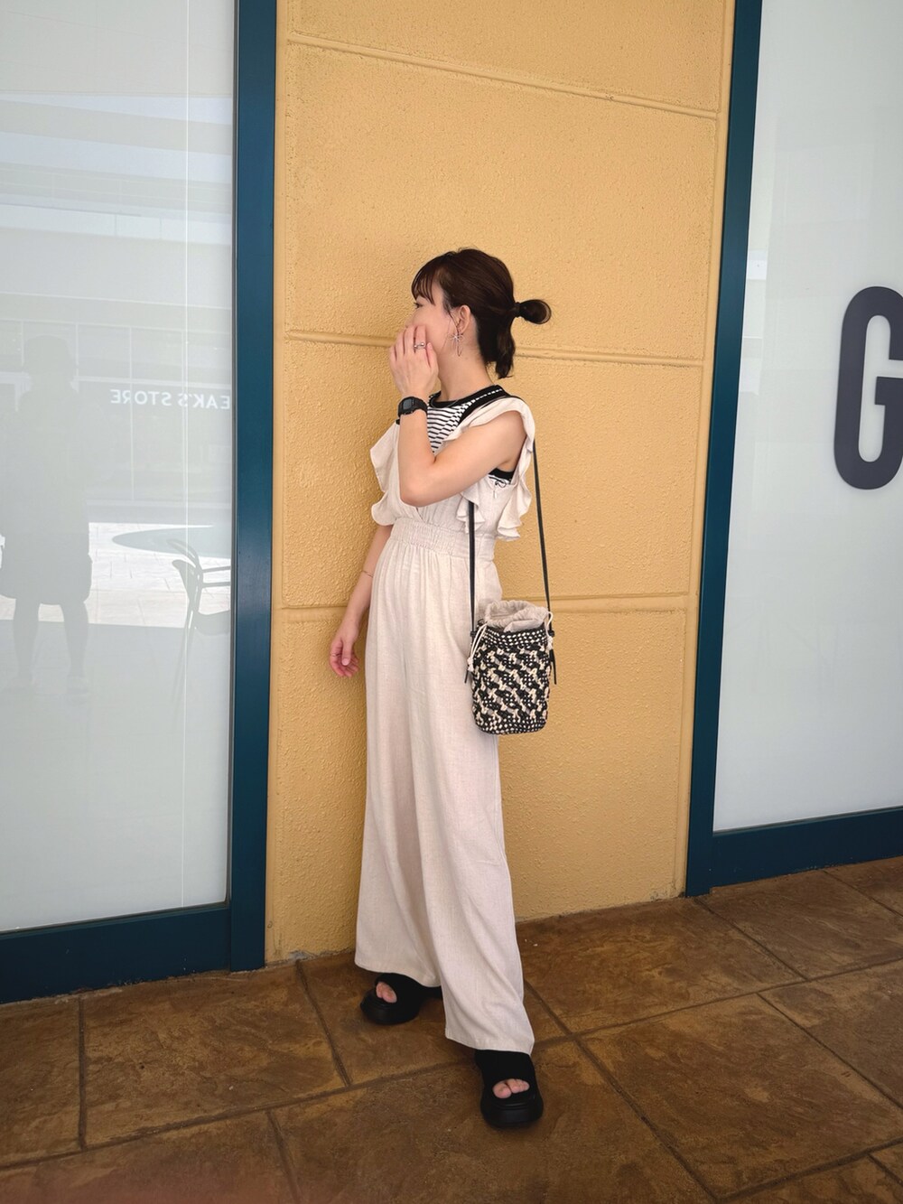 ホワイト系のオールインワン・サロペット、ブラック系のショルダーバッグ、ホワイト系のタンクトップを着用したレディースの夏コーディネートの4枚目の写真