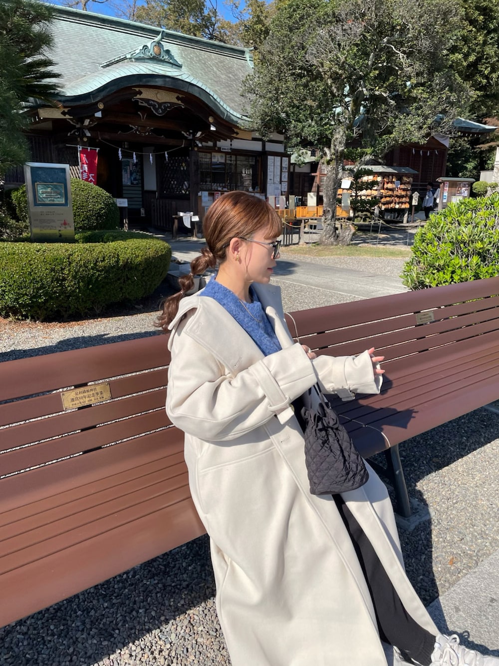 ホワイト系のトレンチコート、ブルー系のニット/セーター、ホワイト系のスニーカーを着用したレディースの秋コーディネートの5枚目の写真