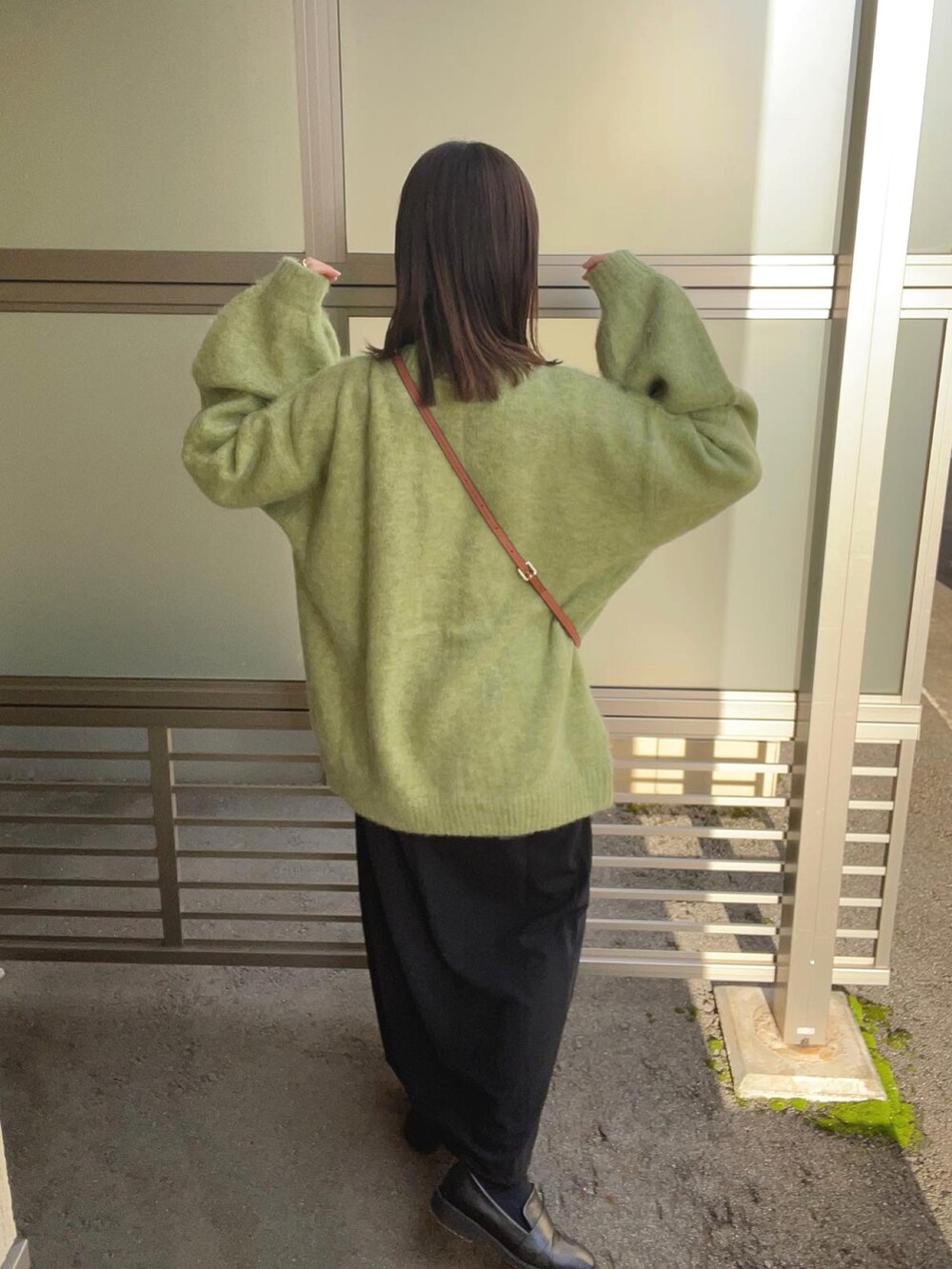 グリーン系のカーディガン/ボレロ、ホワイト系のニット/セーター、ブラック系のスカートを着用したレディースの冬コーディネートの4枚目の写真
