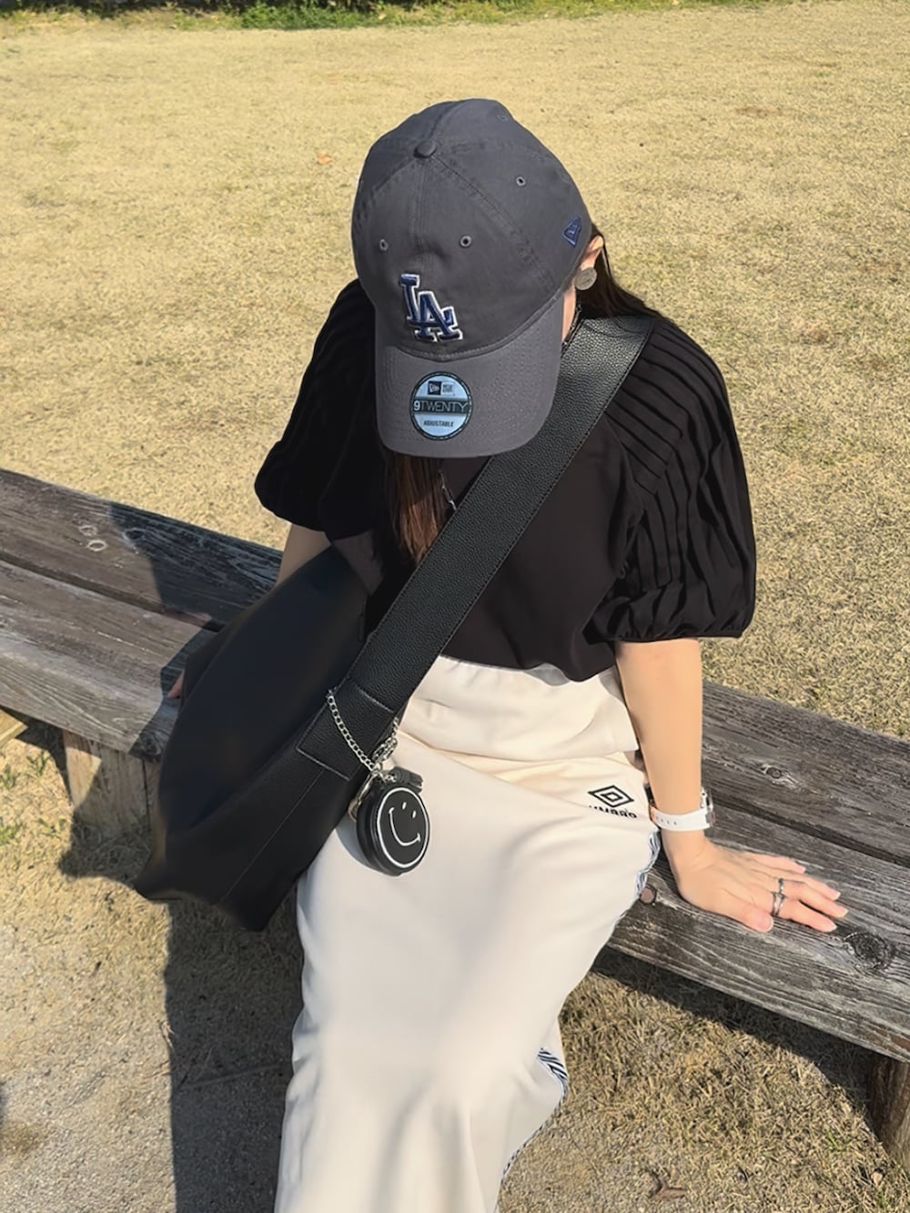 ブラック系のシャツ/ブラウス、ホワイト系のスカート、ベージュ系のスニーカーを着用したレディースの夏コーディネートの2枚目の写真
