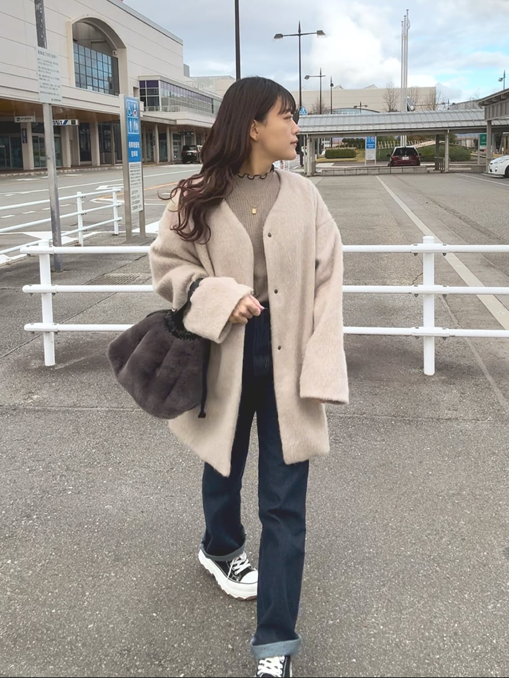 ブラウン系のニット/セーター、ベージュ系のジャケット/アウター、ブルー系のパンツを着用したレディースの冬コーディネートの2枚目の写真