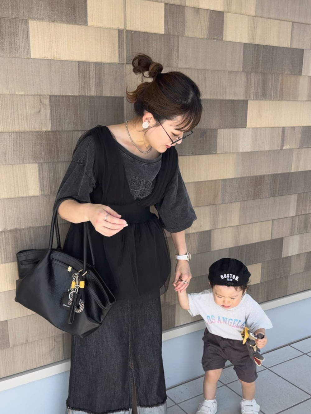 ブラック系のデニムスカート、グレー系のTシャツ/カットソー、ブラック系のベストを着用したレディースの秋コーディネートの5枚目の写真