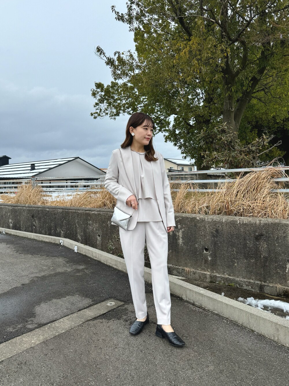 ベージュ系のセットアップ、ブラック系のパンプス、ベージュ系のパンツドレスを着用したレディースの冬コーディネートの5枚目の写真