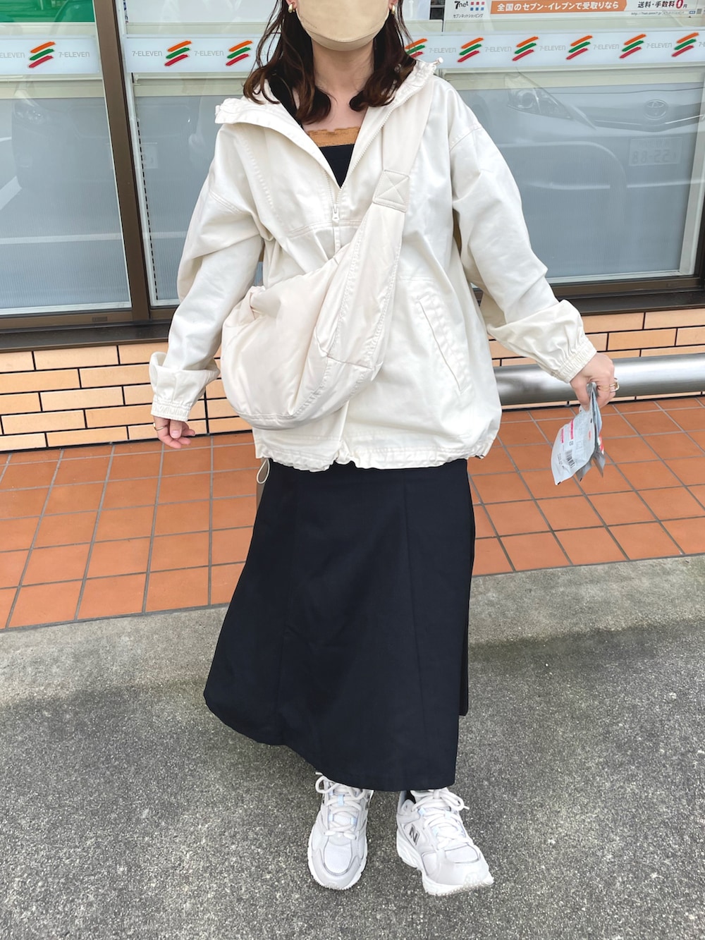 ホワイト系のパーカー、ブラック系のジャンパースカート、オレンジ系のキャミソールを着用したレディースの春コーディネートの5枚目の写真