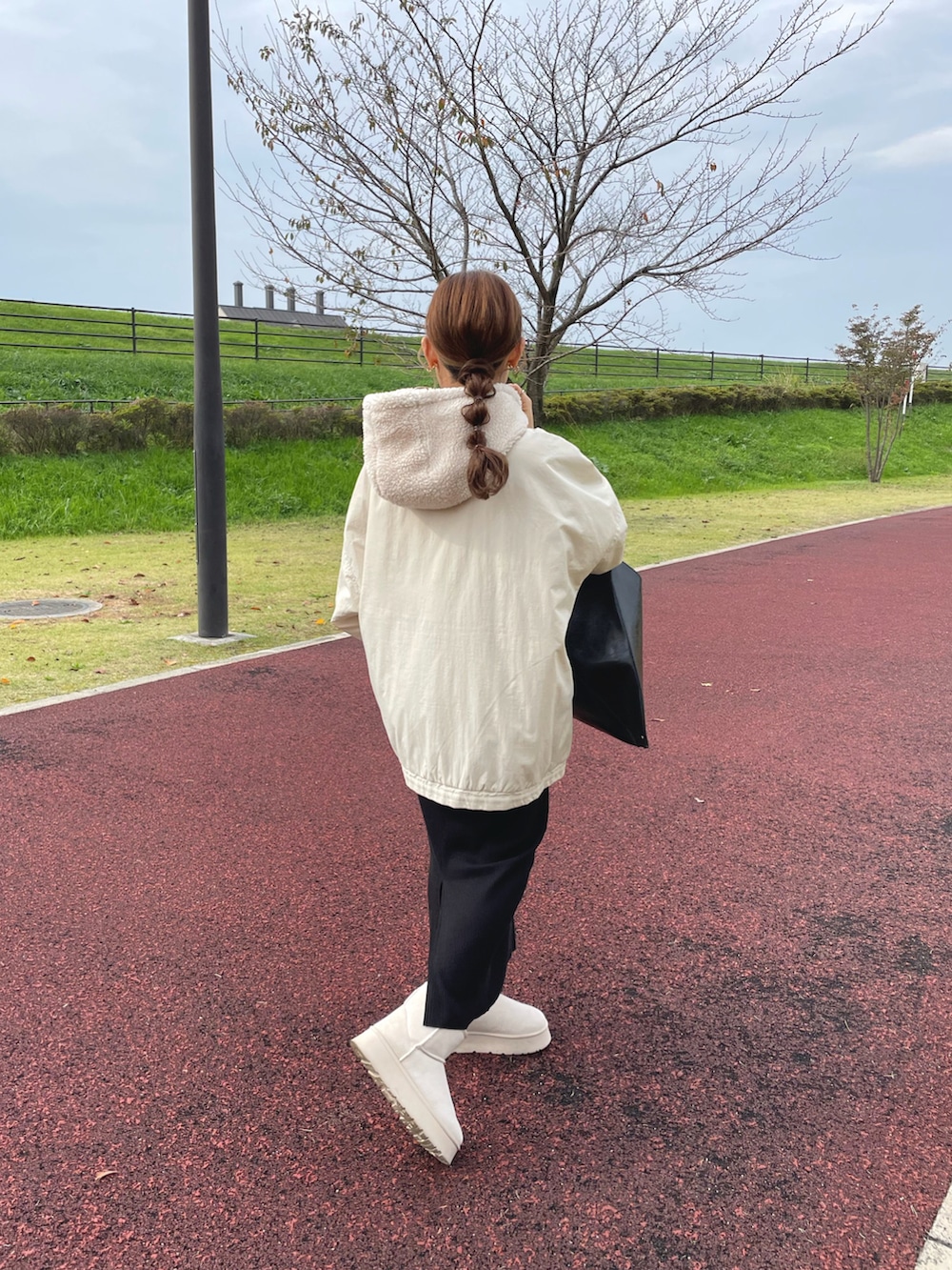 ホワイト系のブルゾン、ブラック系のバッグ、ベージュ系のブーツを着用したレディースの冬コーディネートの4枚目の写真