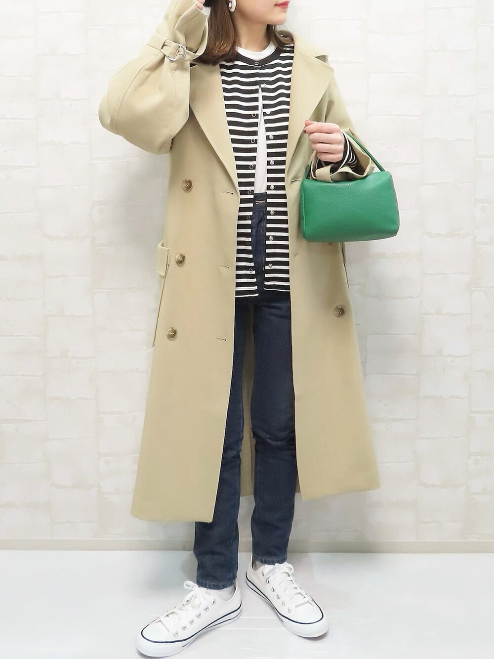 ベージュ系のトレンチコート、ブラック系のカーディガン/ボレロ、ブルー系のデニムパンツを着用したレディースの冬コーディネートの2枚目の写真