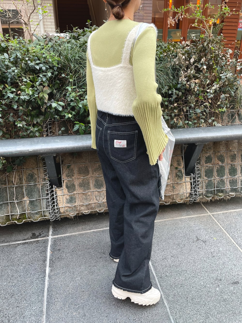 グリーン系のニット/セーター、ホワイト系のベスト、ブラック系のデニムパンツを着用したレディースの春コーディネートの4枚目の写真