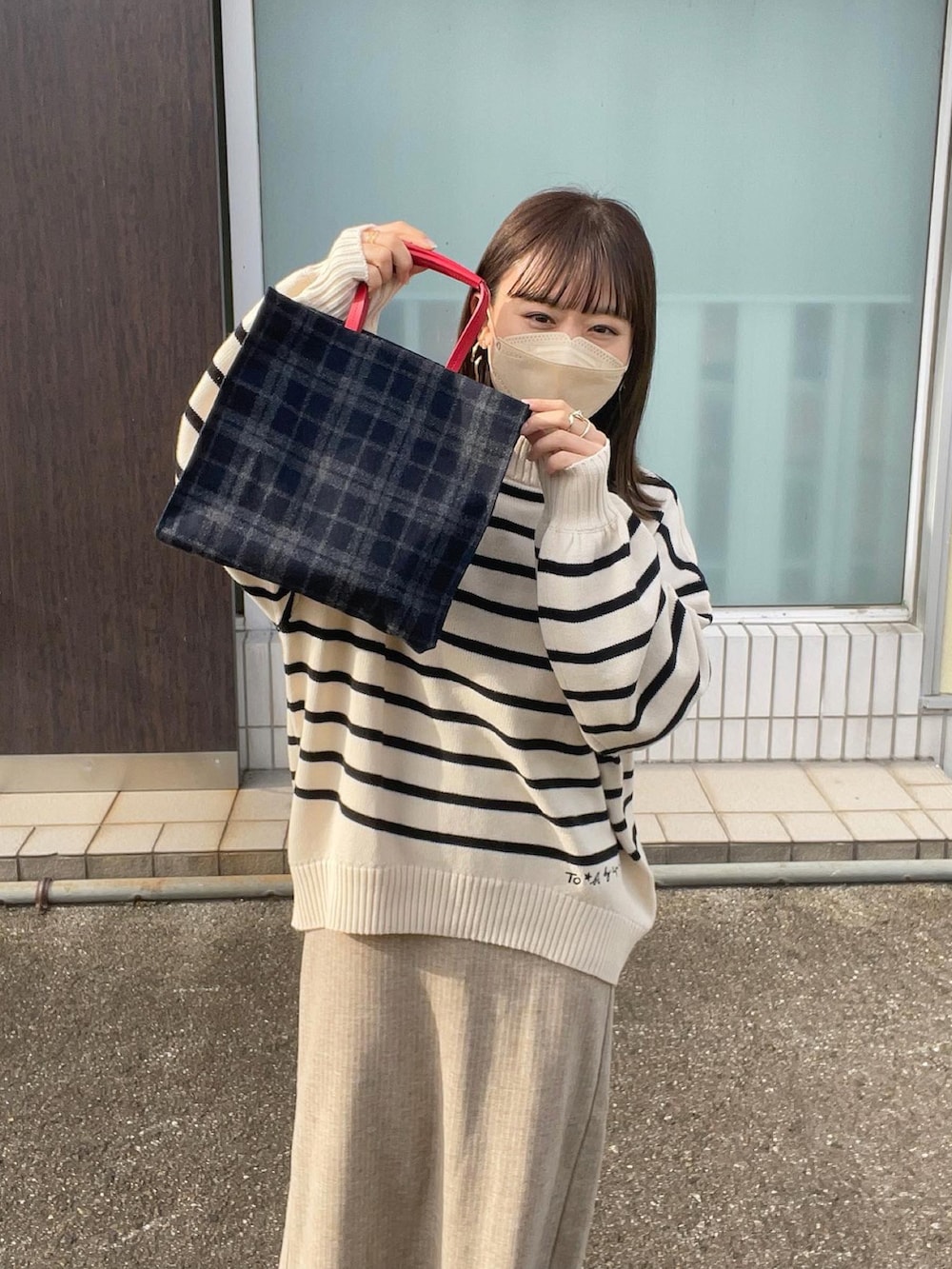 ホワイト系のニット/セーター、ブルー系のトートバッグ、ブラック系のダウンベストを着用したレディースの秋コーディネートの3枚目の写真