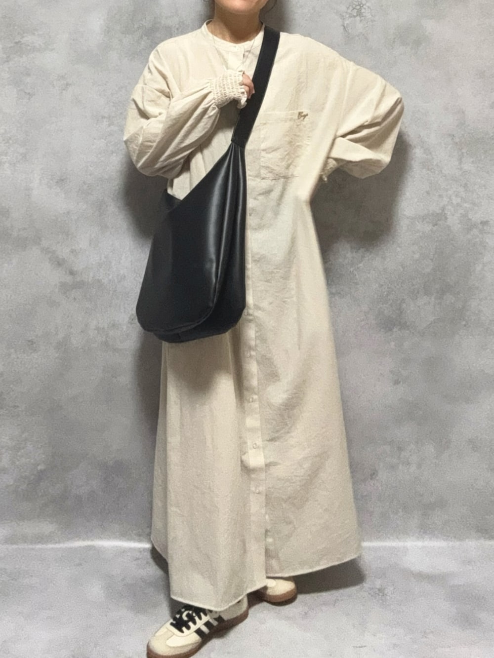 ベージュ系のシャツワンピース、ホワイト系のトップス、ブラック系のバッグを着用したレディースの冬コーディネートの3枚目の写真