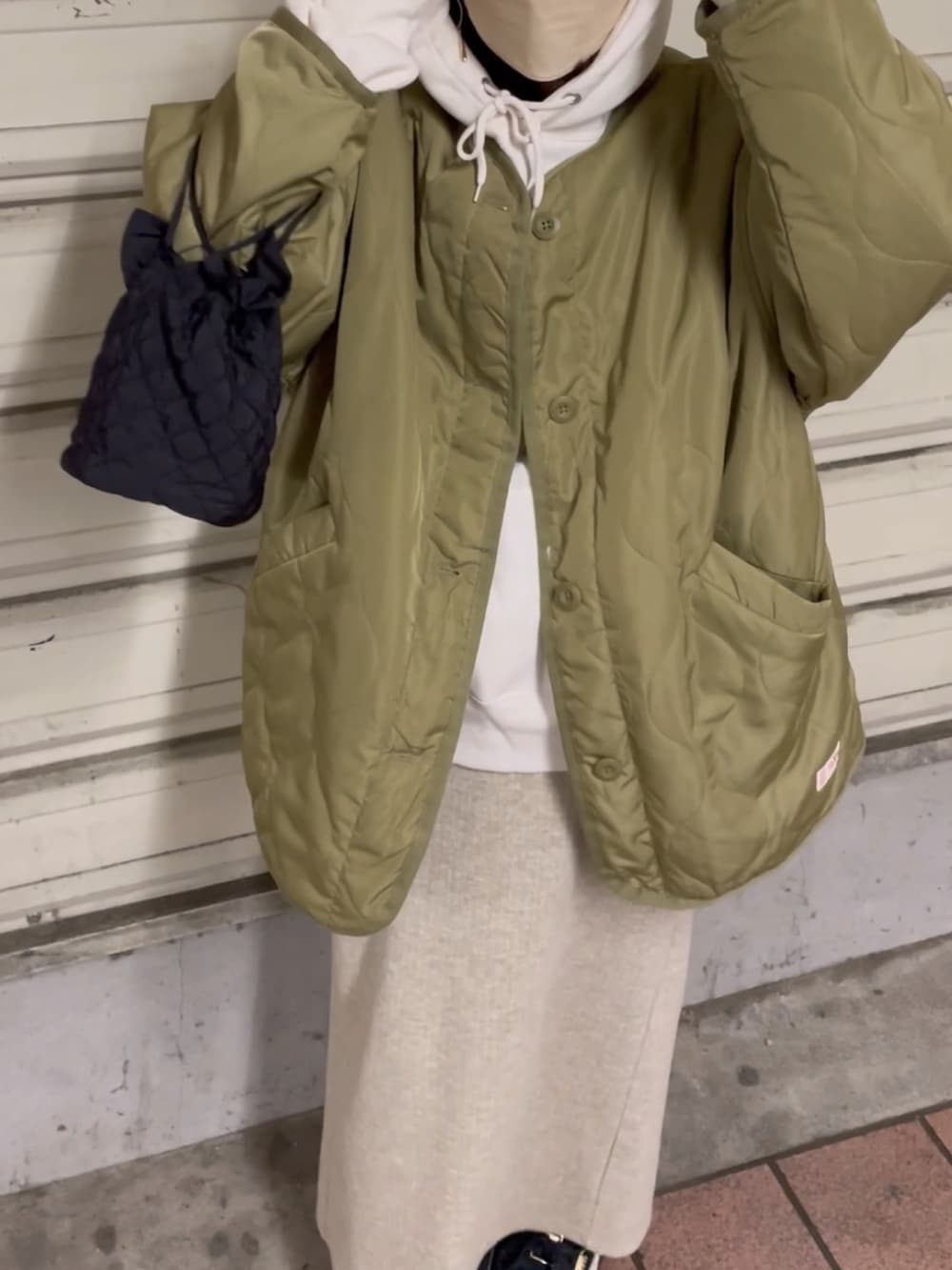 グリーン系のノーカラージャケット、ホワイト系のパーカー、ベージュ系のスカートを着用したレディースの冬コーディネートの4枚目の写真