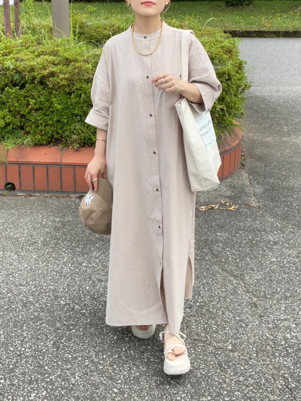 グレー系のシャツワンピース、ホワイト系のトートバッグ、ホワイト系のサンダルを着用したレディースの夏コーディネートの3枚目の写真