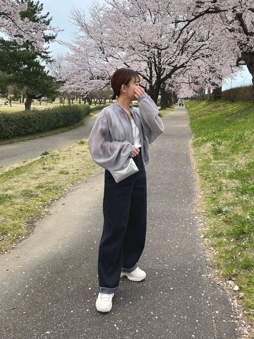 グレー系のブルゾン、ブラック系のデニムパンツ、ホワイト系のシューズを着用したレディースの春コーディネートの4枚目の写真