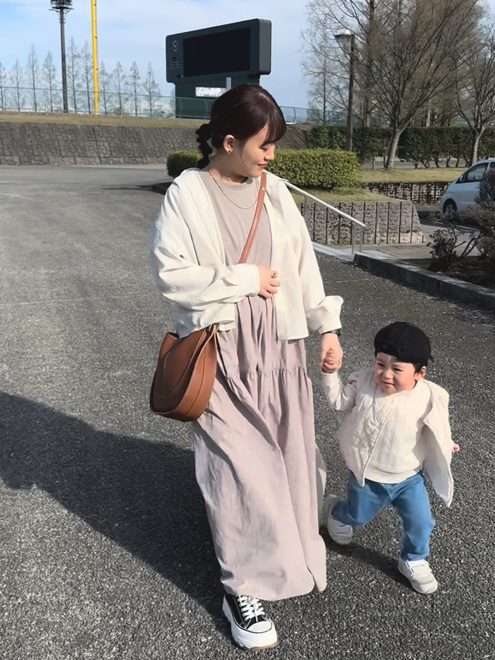 ベージュ系のワンピース、ブラウン系のショルダーバッグ、ブラック系のスニーカーを着用したレディースの春コーディネートの5枚目の写真