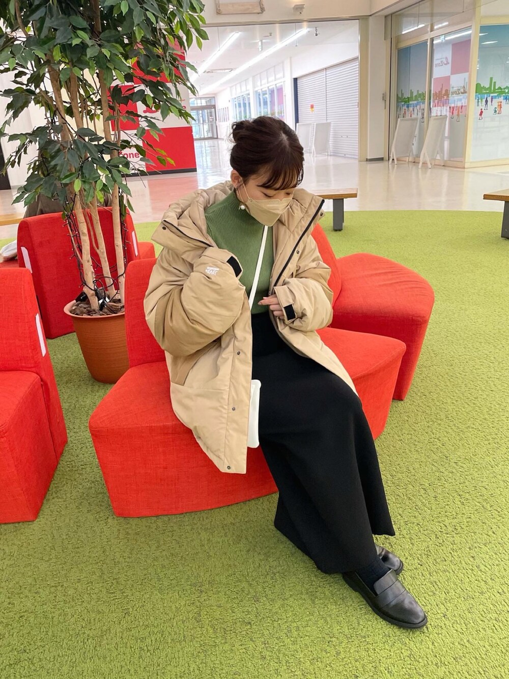 ベージュ系のダウンジャケット/コート、グリーン系のニット/セーター、ブラック系のスカートを着用したレディースの冬コーディネートの2枚目の写真