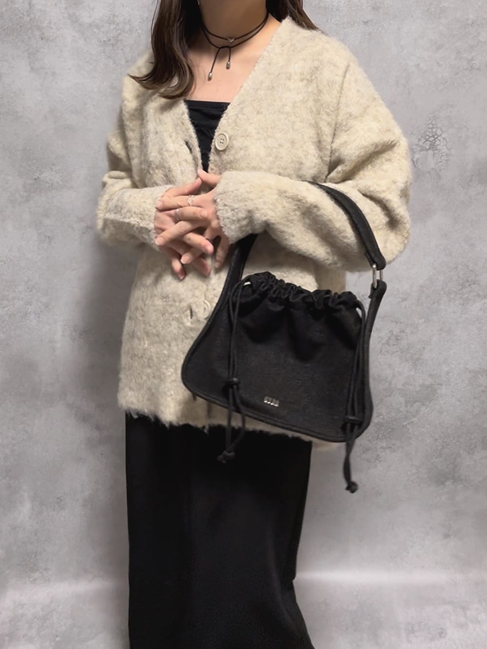 ブラック系のハンドバッグ、ベージュ系のカーディガン/ボレロ、ブラック系のチョーカーを着用したレディースの秋コーディネートの2枚目の写真