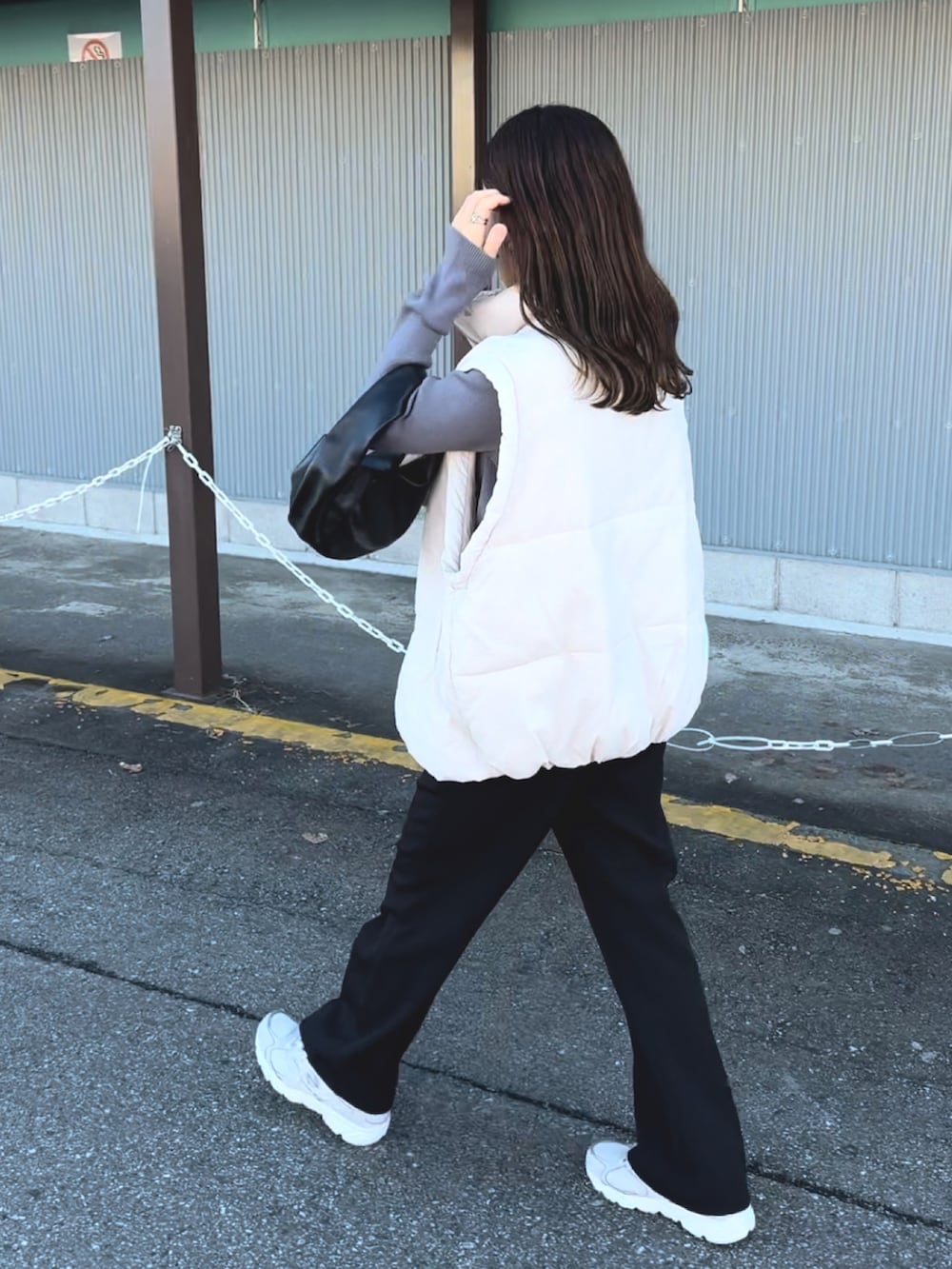 グレー系のニット/セーター、ホワイト系のダウンベスト、ブラック系のスラックスを着用したレディースの冬コーディネートの5枚目の写真