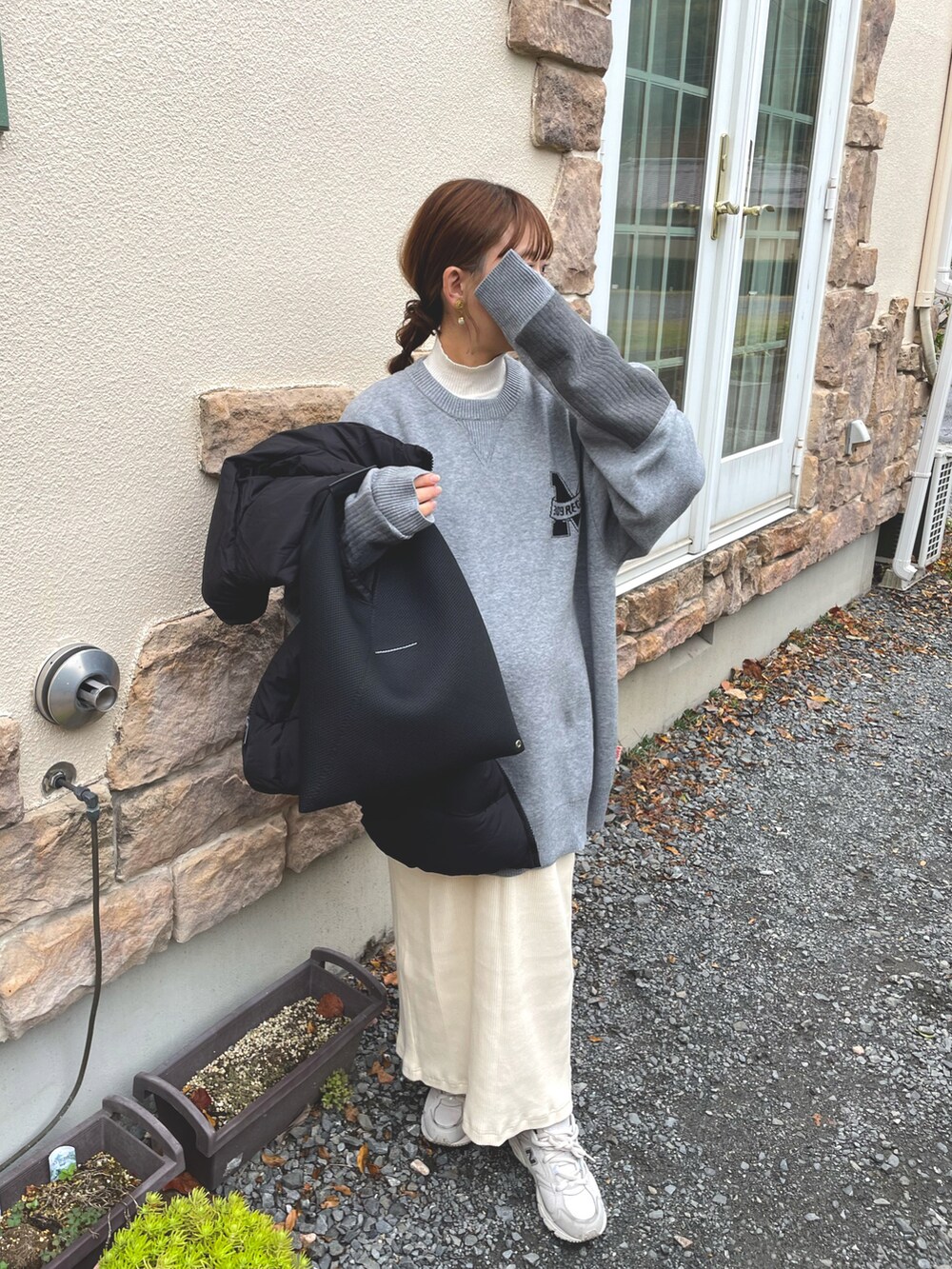 グレー系のニット/セーター、ホワイト系のスカート、ブラック系のベストを着用したレディースの秋コーディネートの3枚目の写真