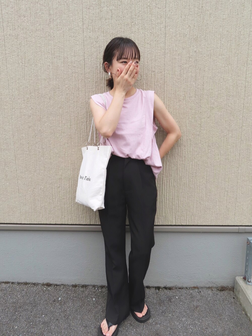 ピンク系のTシャツ/カットソー、ブラック系のスラックス、ホワイト系のトートバッグを着用したレディースの夏コーディネートの3枚目の写真