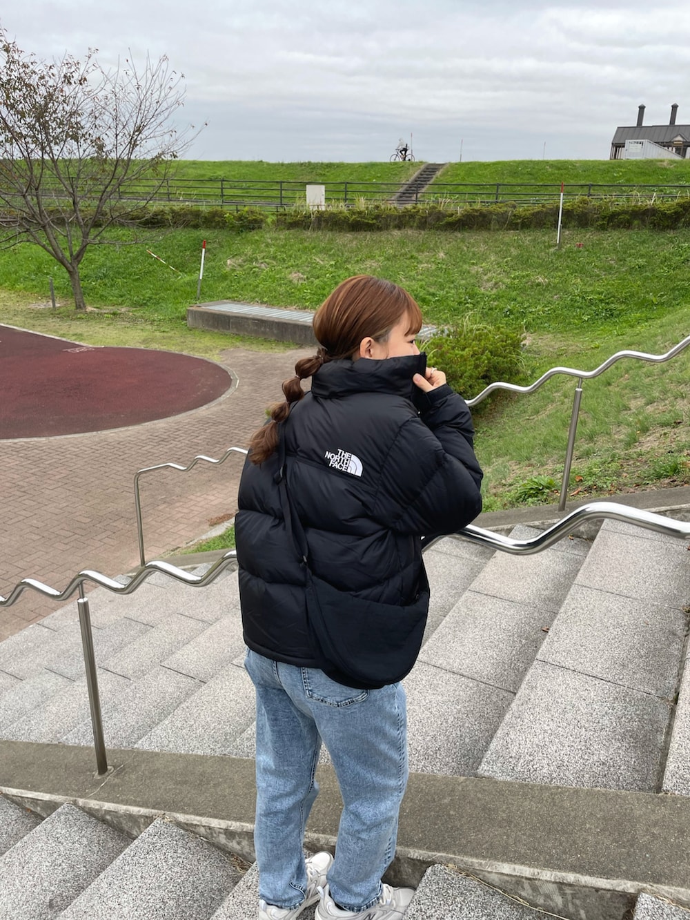 ブラック系のダウンジャケット/コート、ホワイト系のニット/セーター、ブルー系のデニムパンツを着用したレディースの冬コーディネートの4枚目の写真