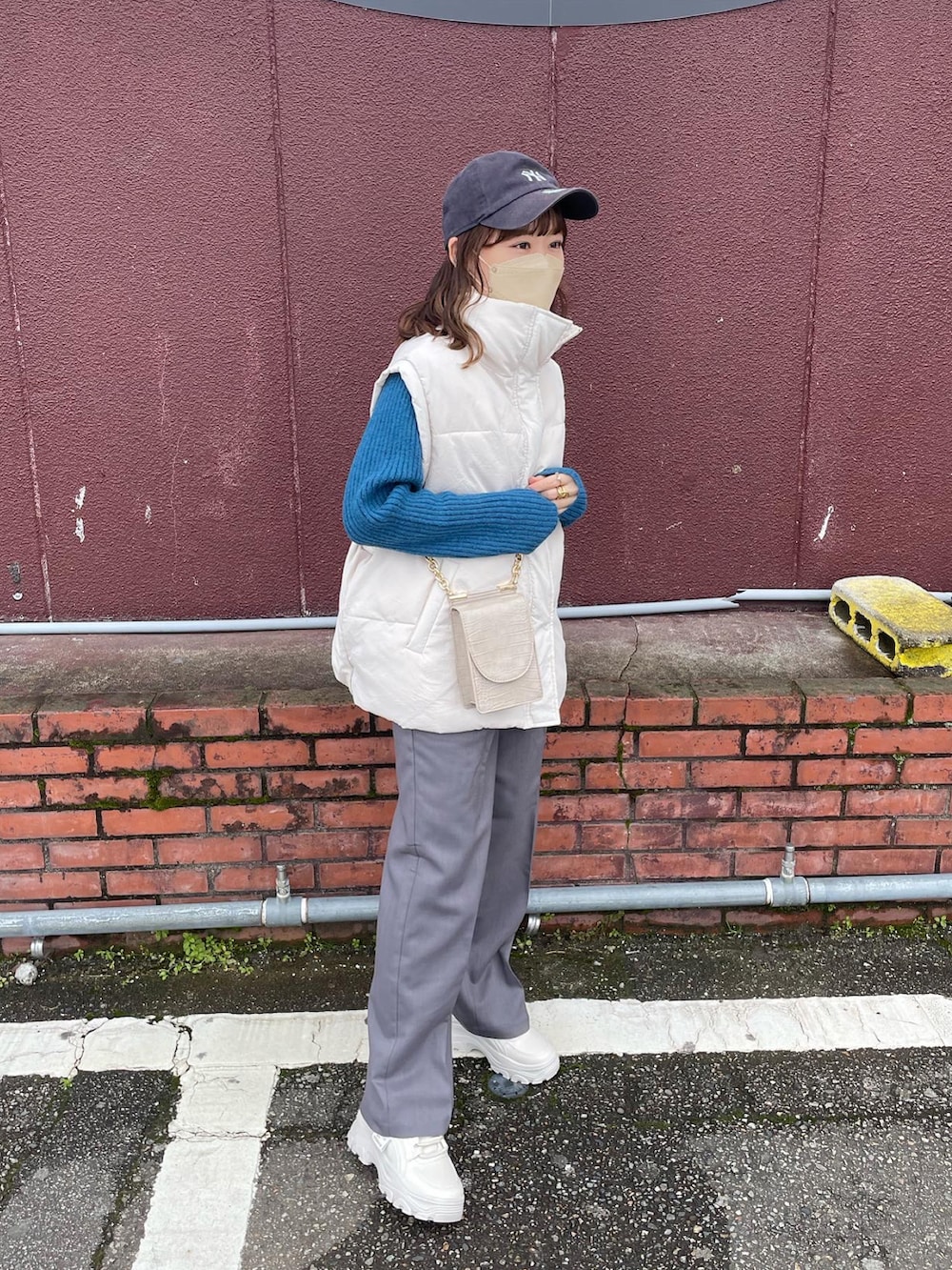 グレー系のパンツ、ブルー系のニット/セーター、ホワイト系のダウンベストを着用したレディースの冬コーディネートの3枚目の写真