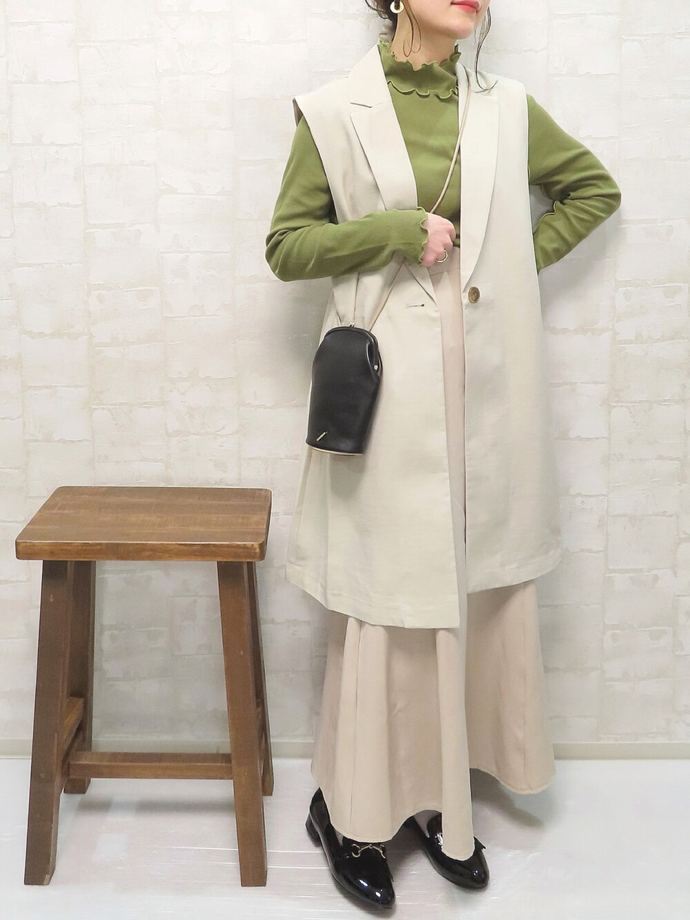 ベージュ系のベスト、グリーン系のTシャツ/カットソー、ベージュ系のスカートを着用したレディースの春コーディネートの3枚目の写真