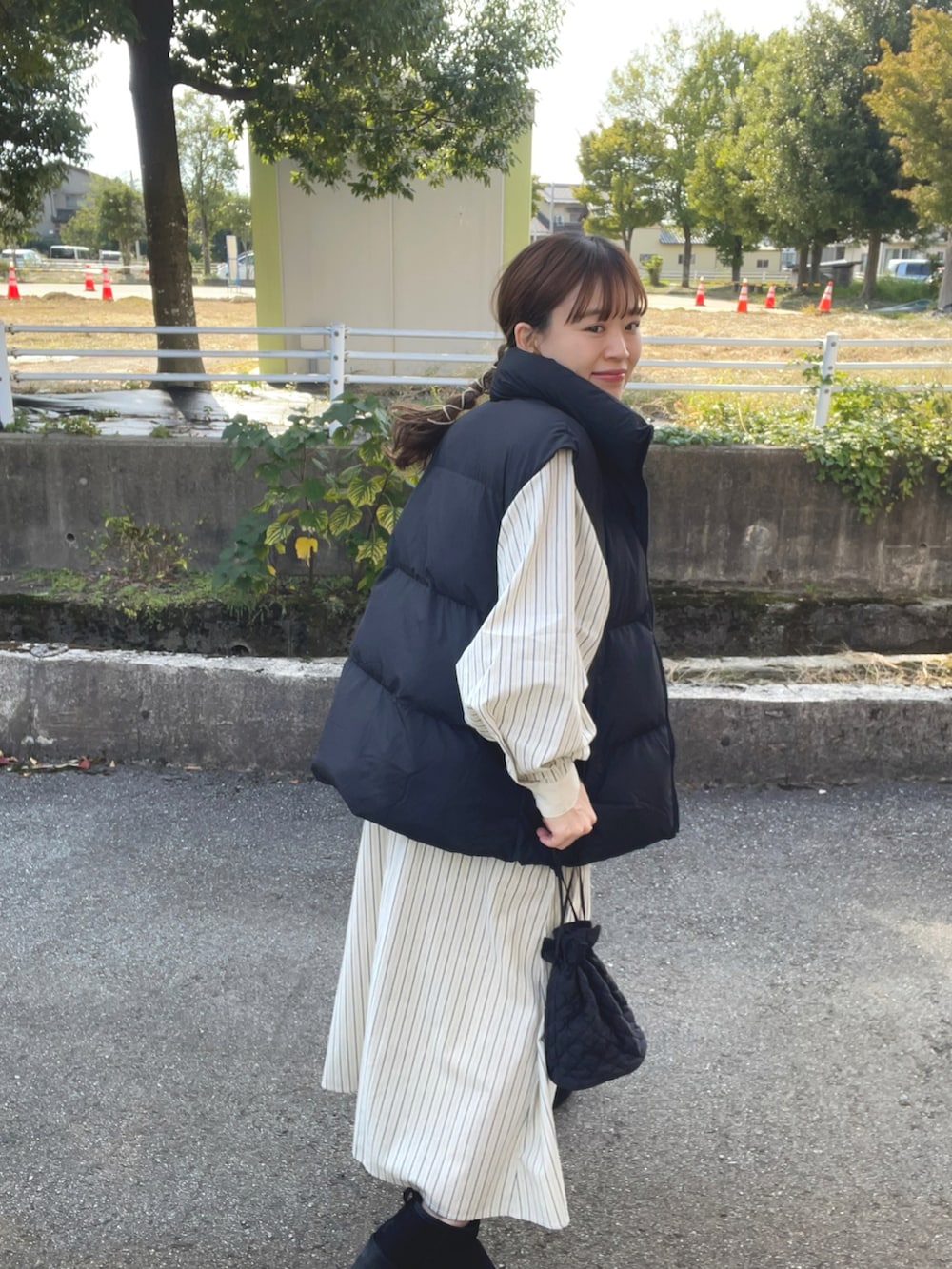 ブルー系のワンピース、ブラック系のベスト、ブラック系のブーツを着用したレディースの秋コーディネートの3枚目の写真