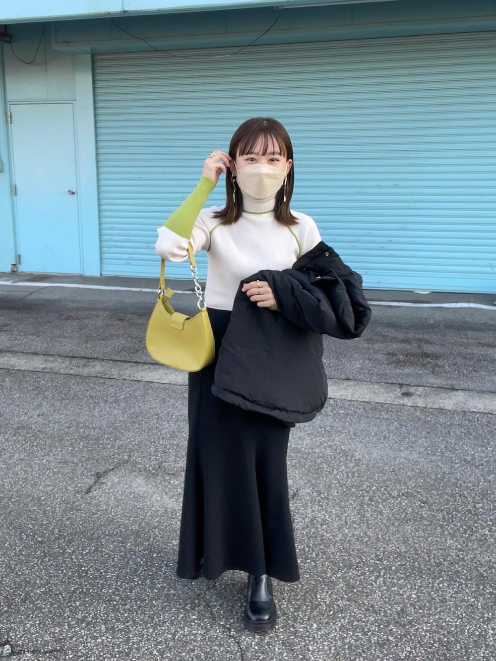 ホワイト系のニット/セーター、ブラック系のダウンベスト、ブラック系のスカートを着用したレディースの秋コーディネートの3枚目の写真