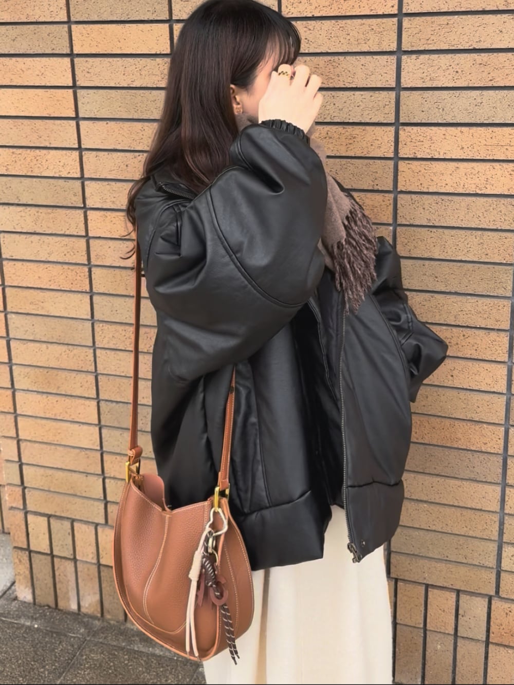 ブラック系のブルゾン、ホワイト系のワンピース、ブラウン系のショルダーバッグを着用したレディースの冬コーディネートの3枚目の写真