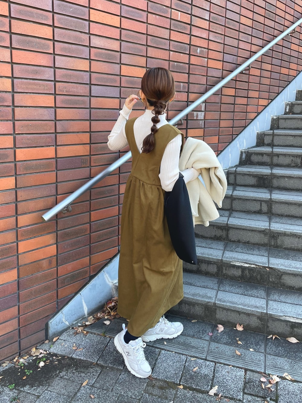 グリーン系のジャンパースカート、ホワイト系のニット/セーター、ホワイト系のカーディガン/ボレロを着用したレディースの冬コーディネートの2枚目の写真