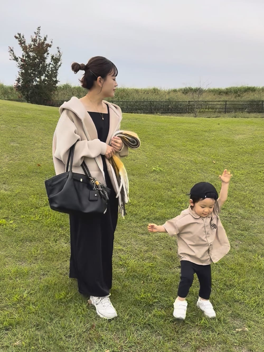 ベージュ系のパーカー、ブラック系のワンピース、ホワイト系のスニーカーを着用したレディースの冬コーディネートの5枚目の写真