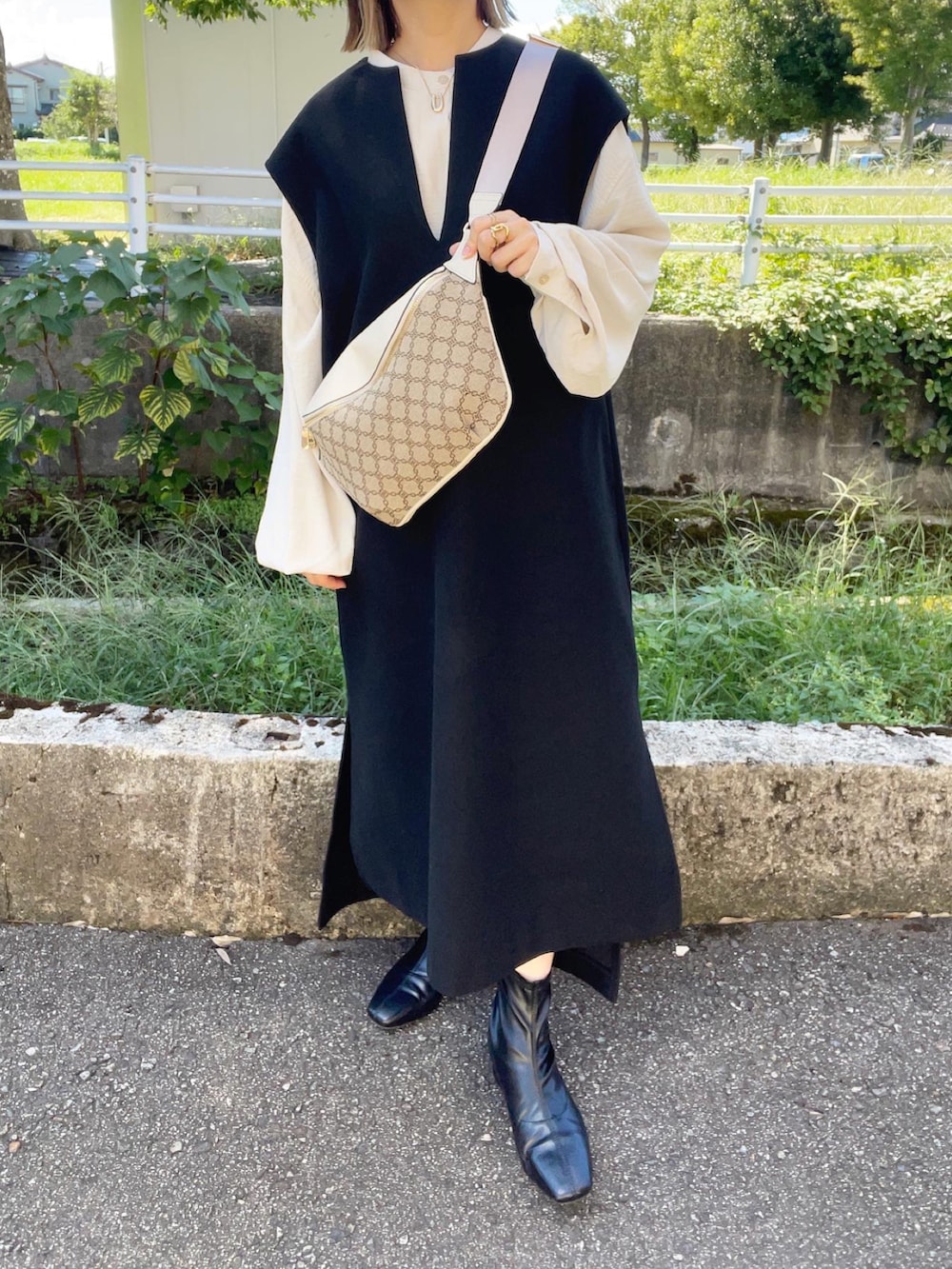 ブラック系のワンピース、ホワイト系のシャツ/ブラウス、ブラック系のブーツを着用したレディースの秋コーディネートの2枚目の写真