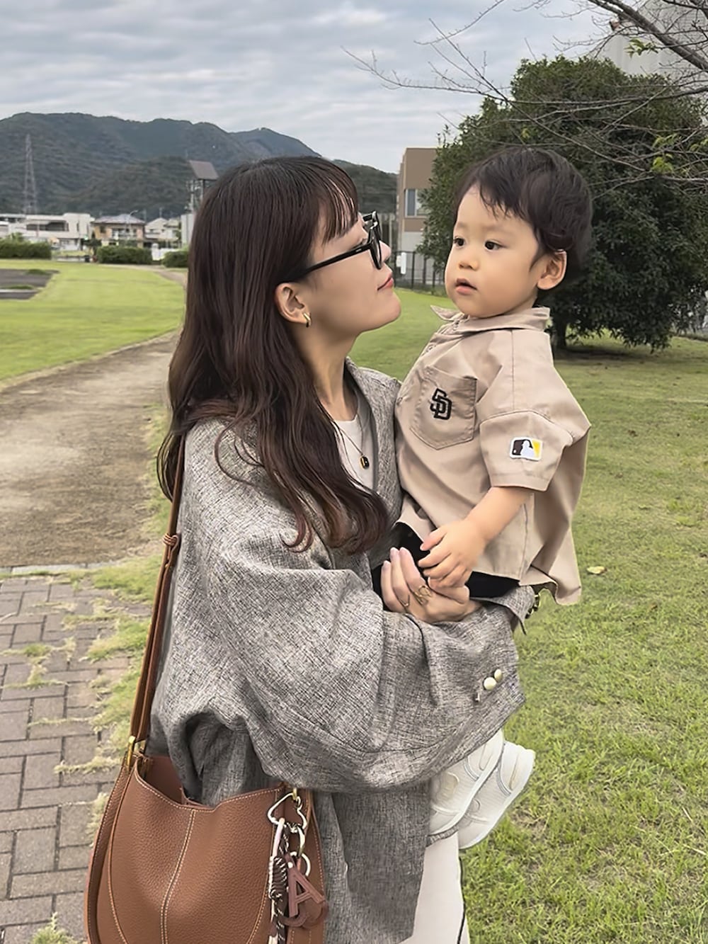 ベージュ系のテーラードジャケット、ベージュ系のワンピース、ブラウン系のショルダーバッグを着用したレディースの秋コーディネートの2枚目の写真