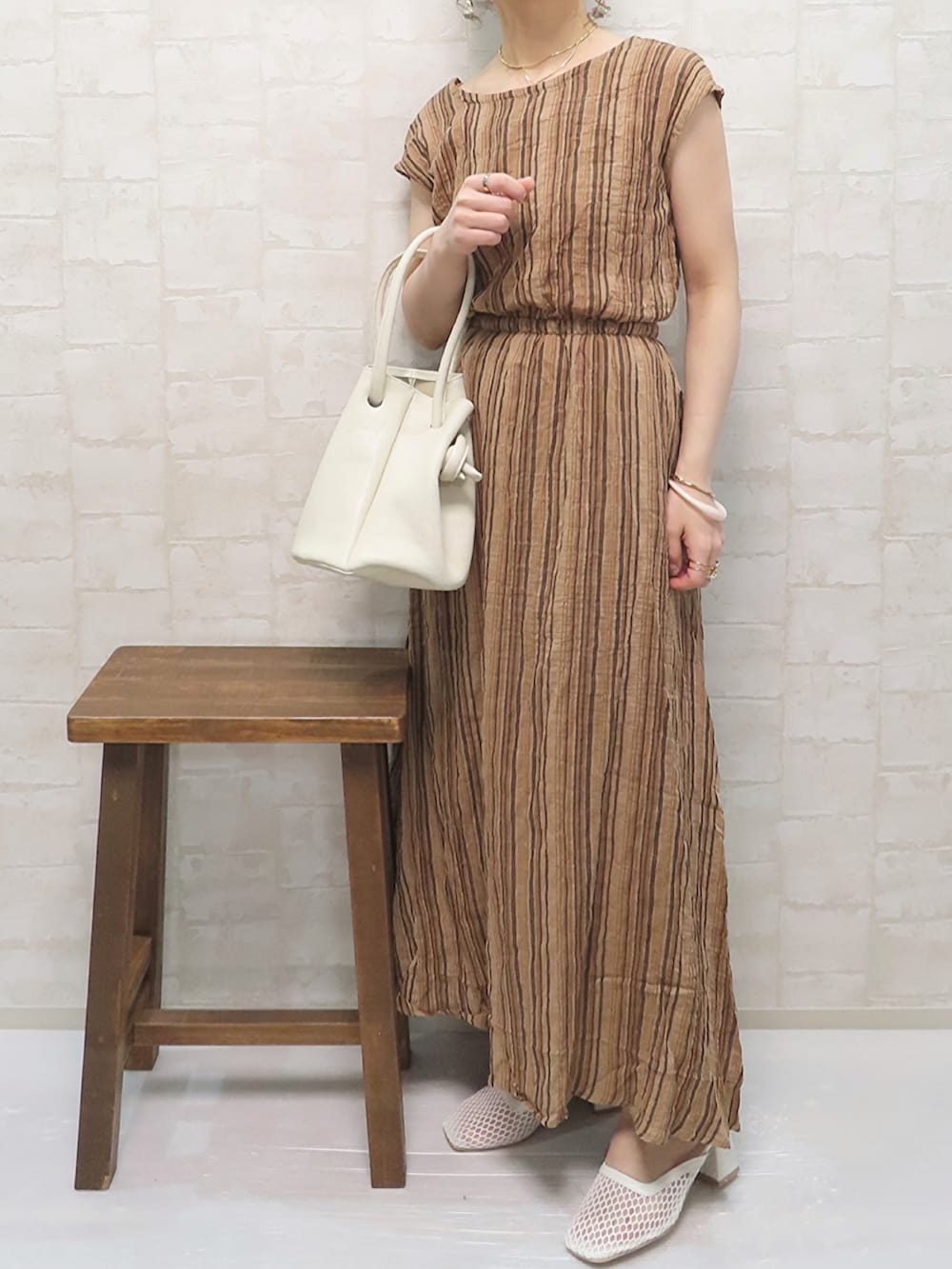 ブラウン系のワンピース、ホワイト系のニット/セーター、ホワイト系のハンドバッグを着用したレディースの春コーディネートの2枚目の写真