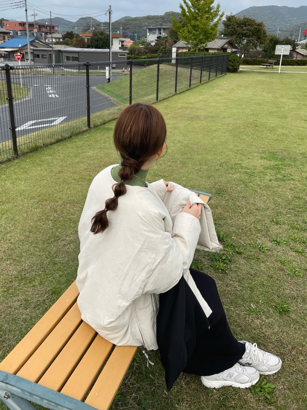 ブラック系のトートバッグ、ホワイト系のスニーカー、グリーン系のニット/セーターを着用したレディースの秋コーディネートの2枚目の写真