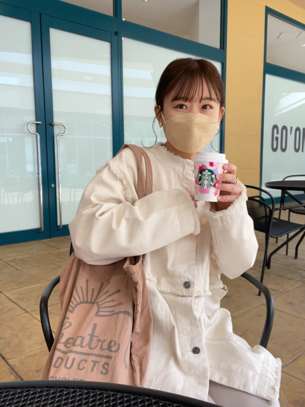 ピンク系のトートバッグ、ホワイト系のデニムジャケット、ホワイト系のスラックスを着用したレディースの春コーディネートの3枚目の写真