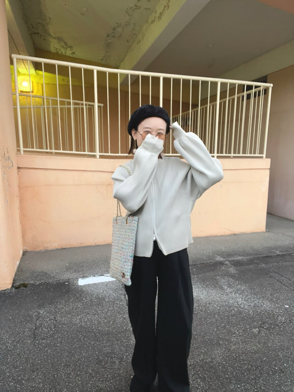 ホワイト系のカーディガン/ボレロ、グリーン系のトートバッグ、ブラック系のパンツを着用したレディースの秋コーディネートの2枚目の写真